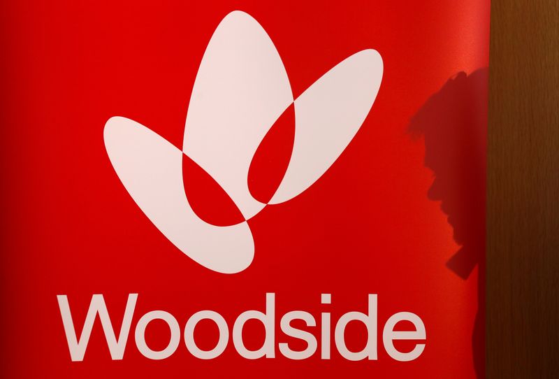 FILE PHOTO: The shadow of a man is cast onto a poster displaying the logo for Woodside Petroleum, Australia's top independent oil and gas company, at a briefing for investors in Sydney,