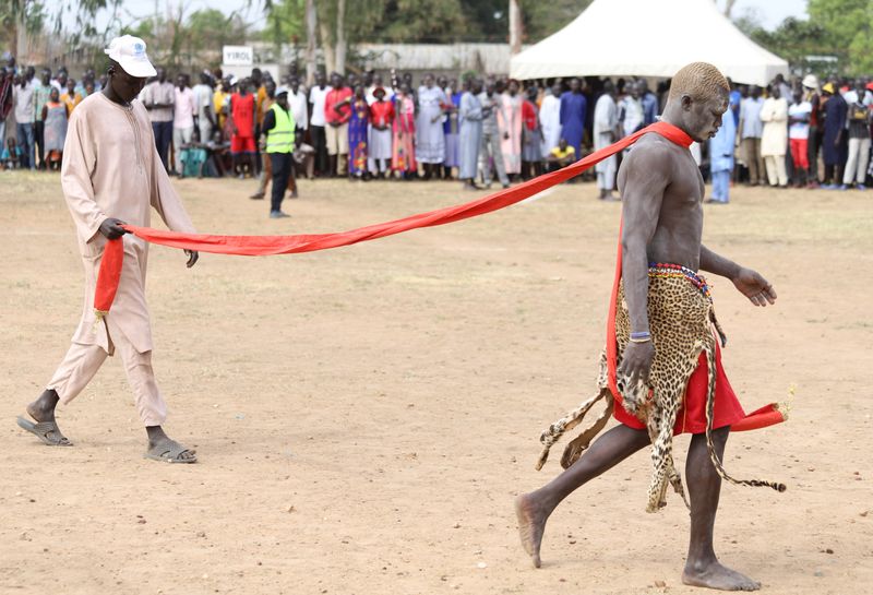 South Sudan's traditional wrestler Alijok Nhial is escorted before competing in a peace match during national championships in Juba