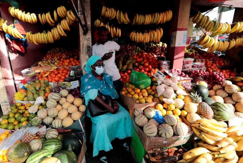 FILE PHOTO: A woman wears a protective face mask as she waits to get her change after buying fruits in Dakar
