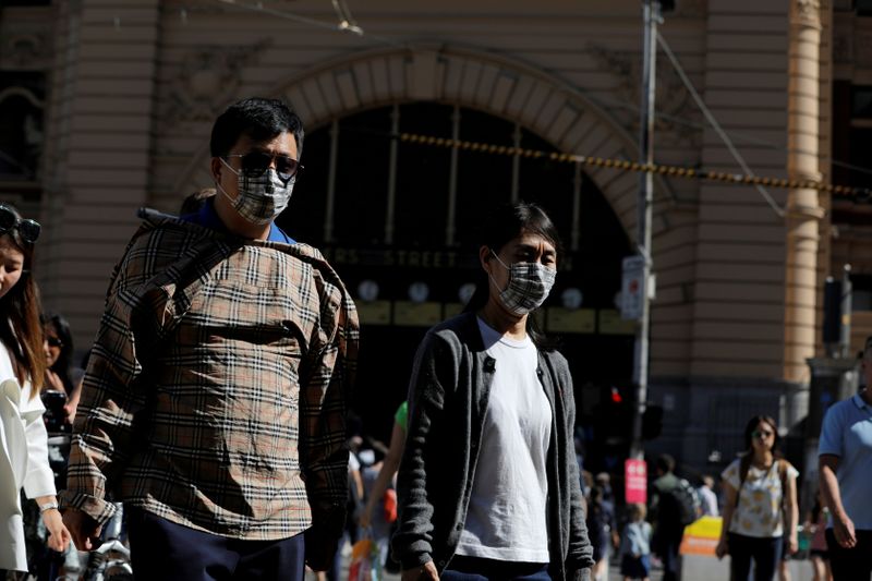 FILE PHOTO: People wearing face masks walk by Flinders Street Station after cases of the coronavirus were confirmed in Melbourne