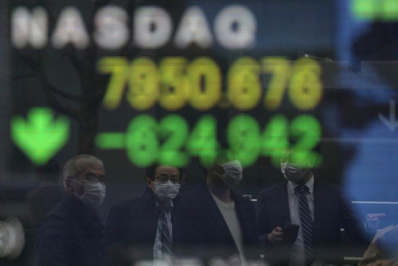 FILE PHOTO: People wearing protective face masks are reflected in a stock quotation board outside a brokerage in Tokyo