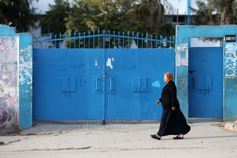 A Palestinian woman walks past a United Nations-run school closed as a precaution measure against coronavirus, in Khan Younis in the southern Gaza Strip