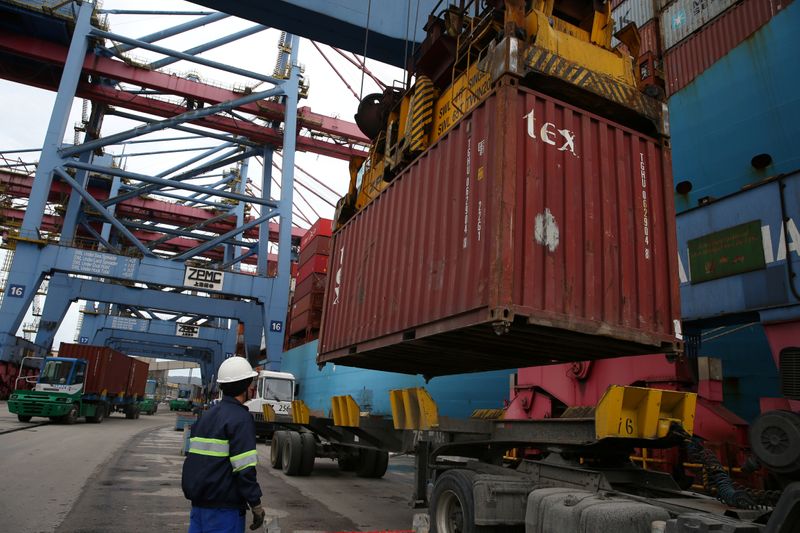 A worker observes a container being placed on top of a truck at the Port of Santos in Santos