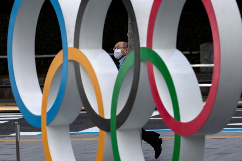 A man wearing a protective face mask, following an outbreak of the coronavirus disease (COVID-19), walks past the Olympic rings in front of the Japan Olympics Museum in Tokyo