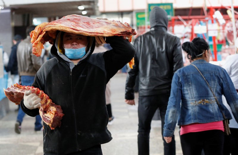 A worker wearing a protective face mask carries meat at a local food market in Almaty