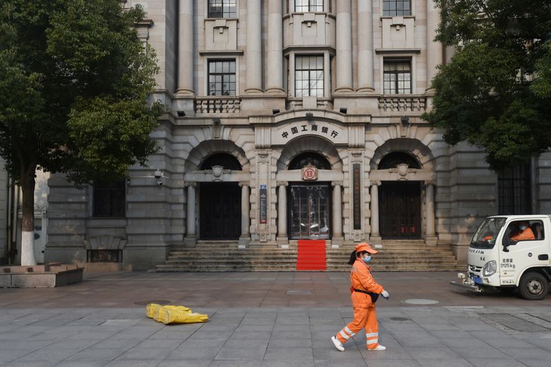 Sanitation worker wearing a face mask walks past a branch of ICBC in Wuhan