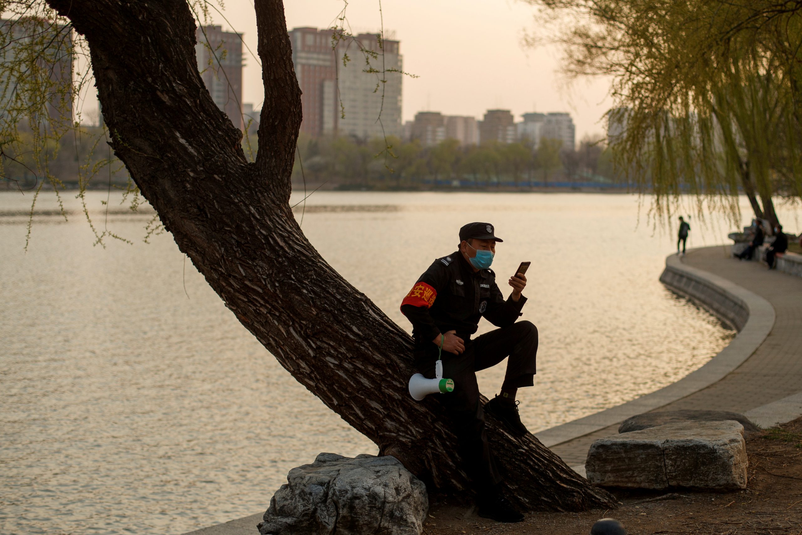 A security guard wearing a protective mask sits on a tree at a park, as the country is hit by an outbreak of the novel coronavirus disease (COVID-19), in Beijing