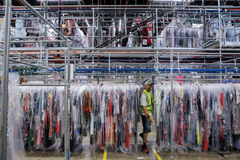 A person moves through clothing in the storage area at Rent the Runway's 