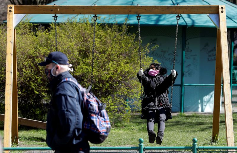 A woman wearing a face mask sits on a swing in Prague