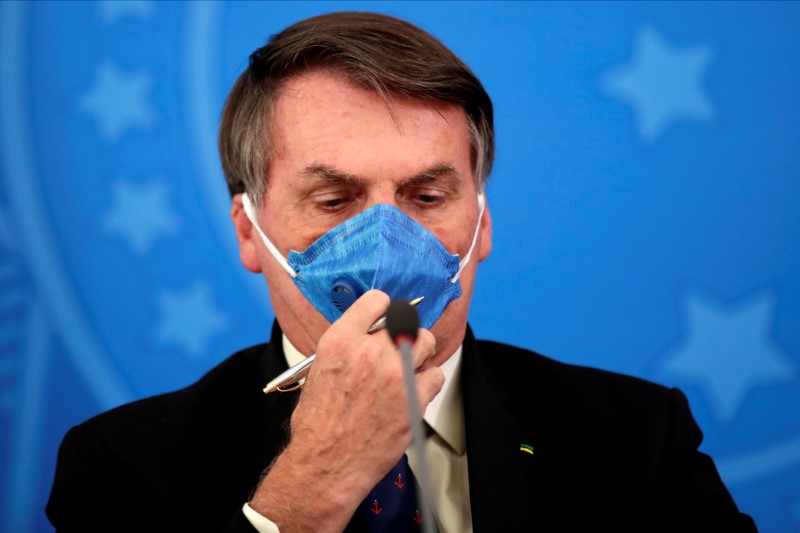 Brazil's President Jair Bolsonaro adjusts his protective face mask at a press statement during the coronavirus disease (COVID-19) outbreak in Brasilia