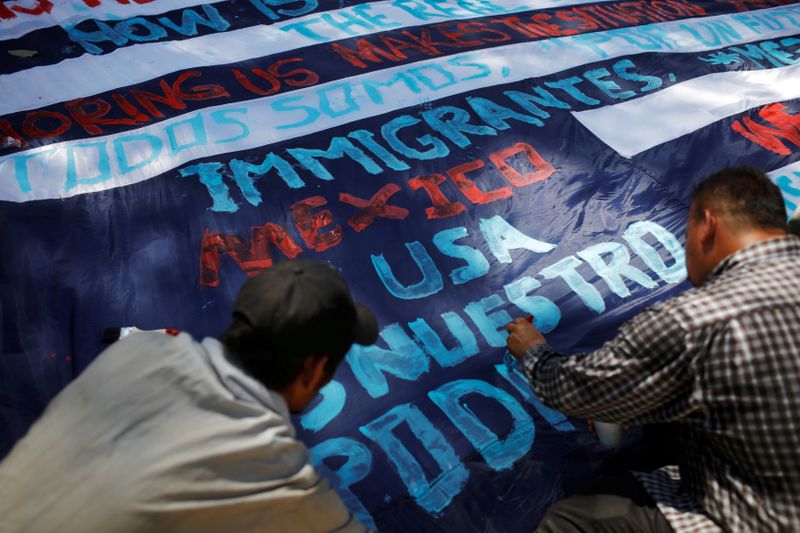 FILE PHOTO: Migrants travelling to the U.S. paint a banner in an improvised shelter in Tecun Uman