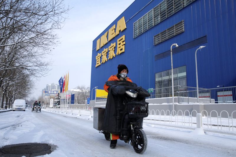 Clean worker wearing a face mask drives past a closed IKEA store in Beijing