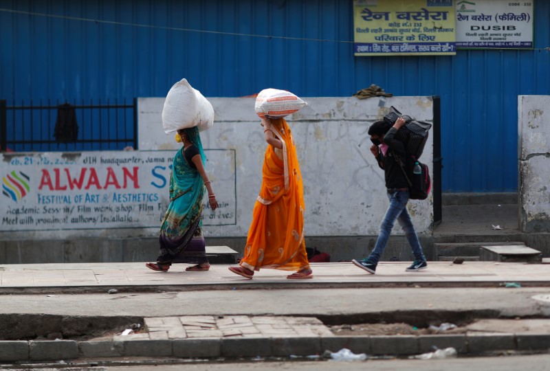 People carrying their luggage walk towards a bus station to return to their cities and villages during lockdown by the authorities to limit the spreading of coronavirus disease (COVID-19), in New Delhi