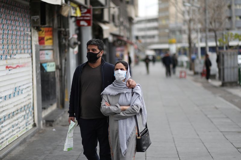 Couple wear protective face masks, amid fear of coronavirus disease (COVID-19), as they walk at Enghelab square, in Tehran
