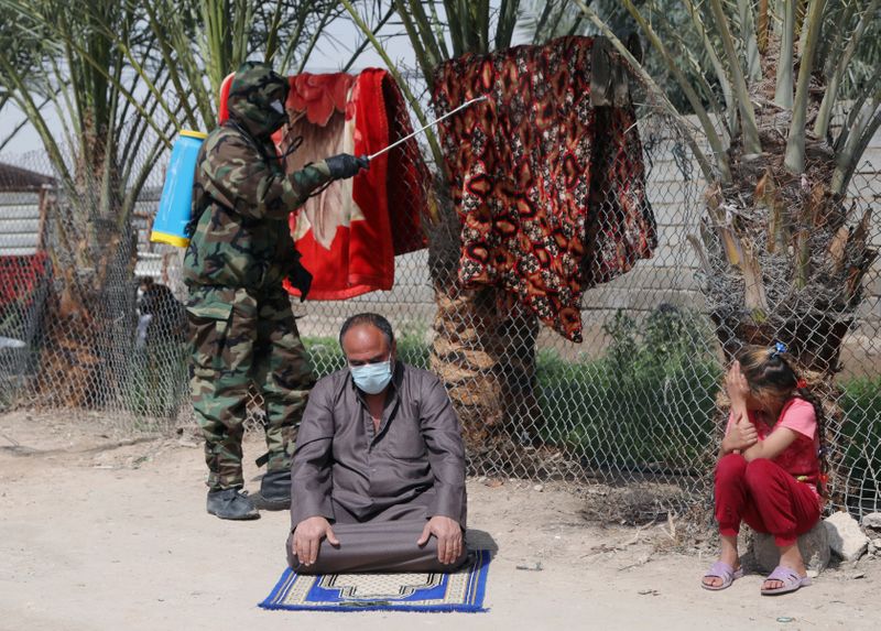 A member of the civil defense team sprays disinfectant to sanitize an area in the neighbourhood of the house of the person who was diagnosed with coronavirus and died, in Kerbala