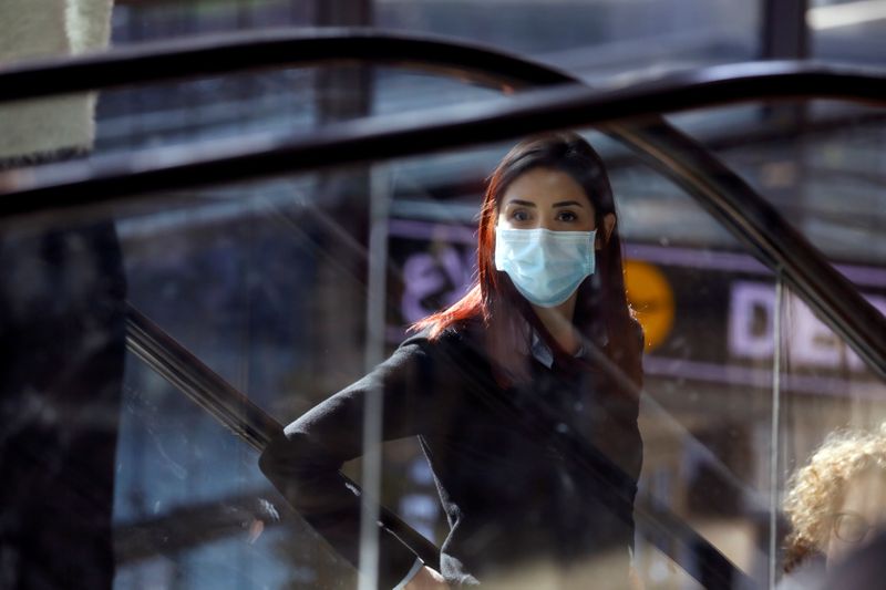 FILE PHOTO: A woman wearing a mask looks on at a terminal at Ben Gurion International airport in Lod, near Tel Aviv, Israel