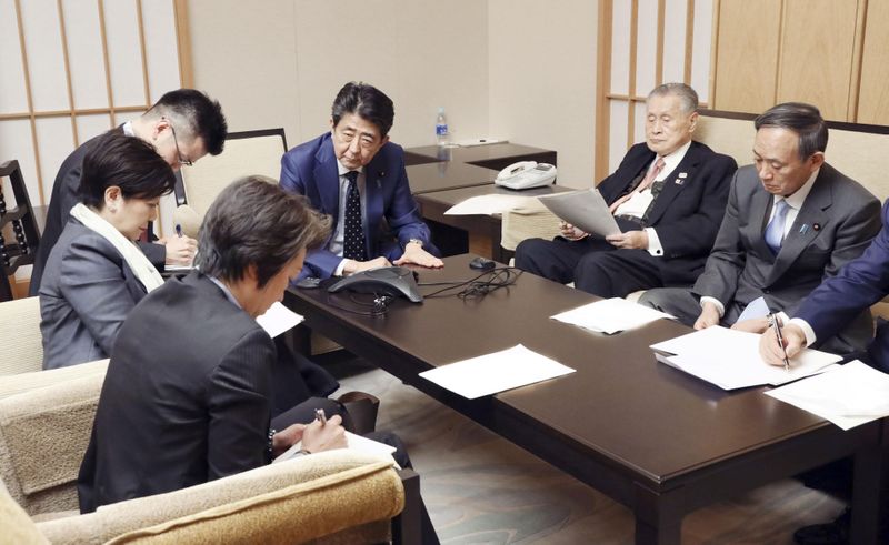 Japan's Prime Minister Shinzo Abe, President of the Tokyo 2020 Organizing Committee Yoshiro Mori, Tokyo Governor Yuriko Koike, and ministers attend a telephone conference with IOC President Bach in Tokyo