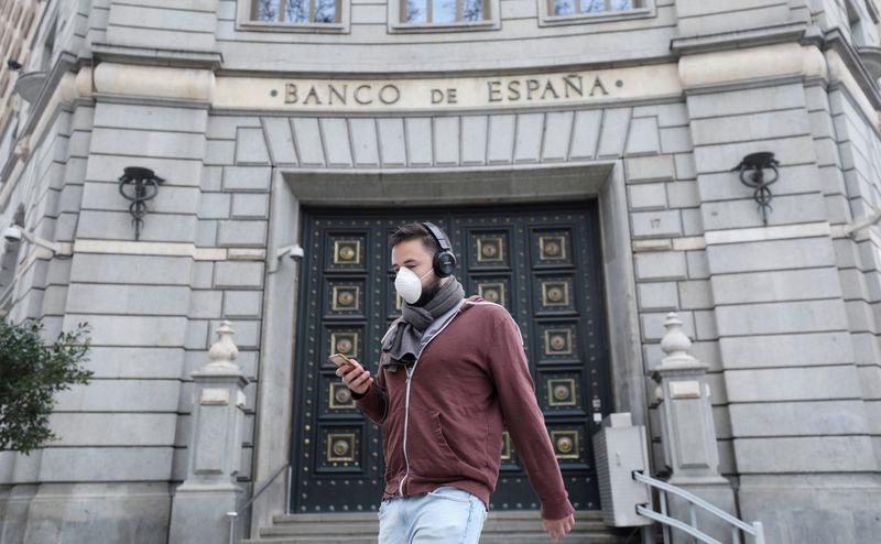 FILE PHOTO: A man wears a protective face mask as he walks past Banco de Espana (Bank of Spain), amidst concerns over coronavirus outbreak, in Barcelona