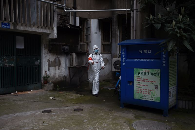 Community worker in protective suit disinfects a residential compound in Wuhan