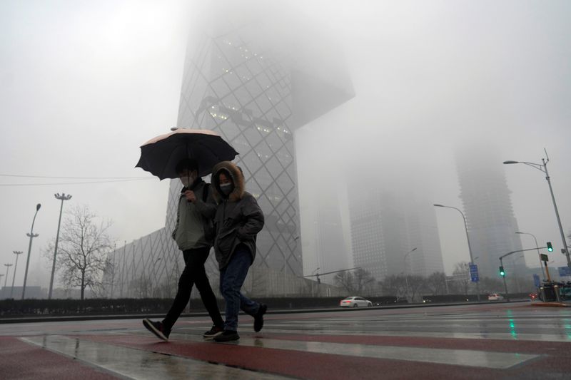 Pedestrians wearing face masks walk amid rainfall at the Central Business District, as the country is hit by a novel coronavirus outbreak, in Beijing