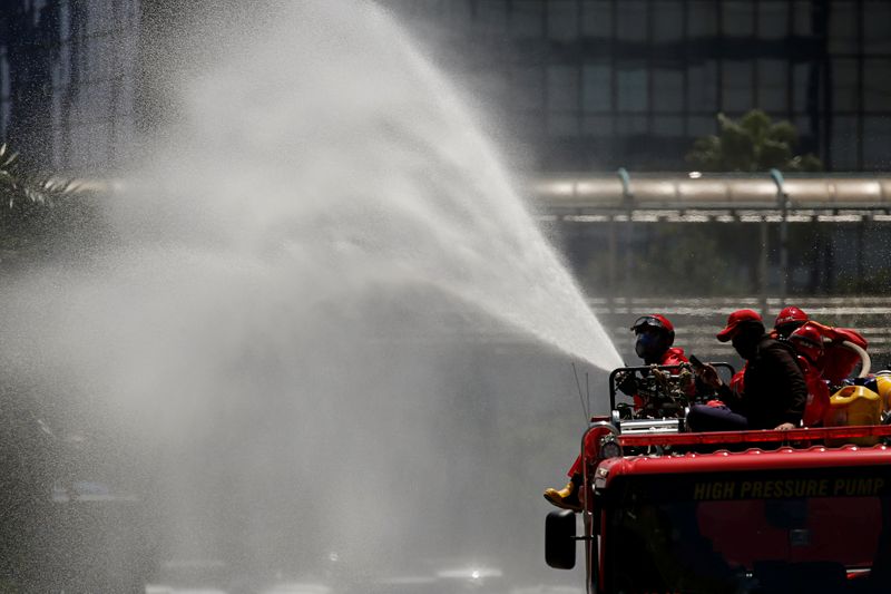Firefighters spray disinfectant using high pressure pump truck to prevent the spread of coronavirus disease (COVID-19), on the main road in Jakarta