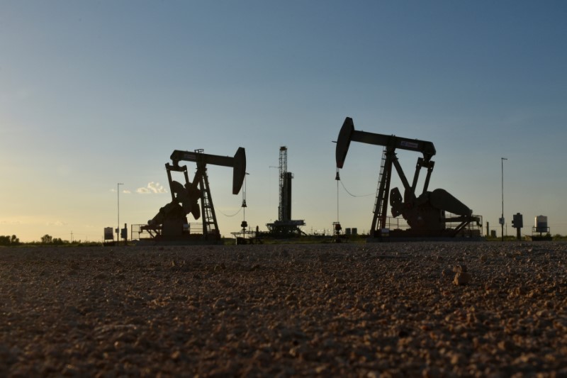 FILE PHOTO: FILE PHOTO: Pump jacks operate in front of a drilling rig in an oil field in Midland