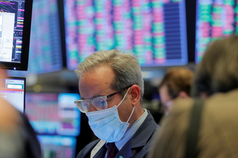 FILE PHOTO: A trader wears a mask as he works on the floor of the New York Stock Exchange (NYSE) as the building prepares to close indefinitely due to the coronavirus disease (COVID-19) outbreak in New York