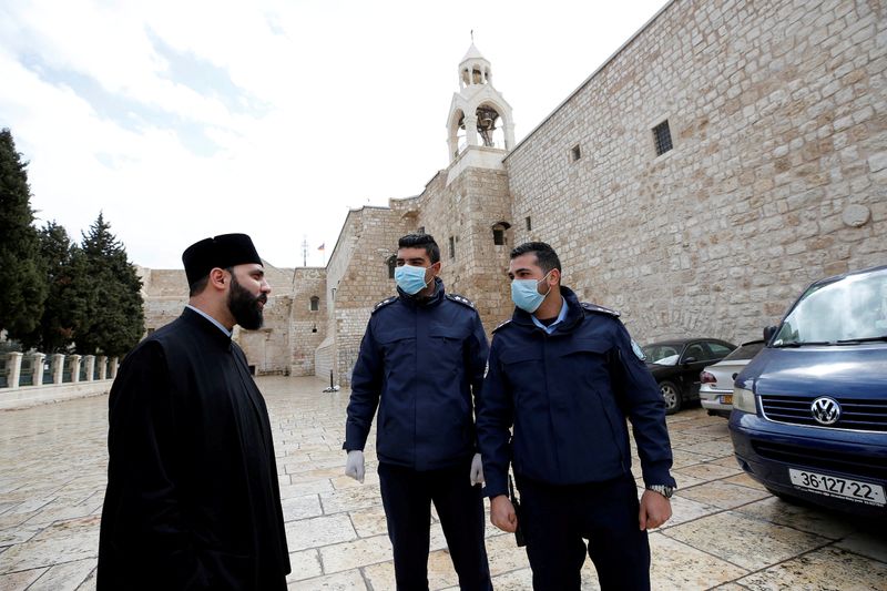 FILE PHOTO: Palestinian police officers stand guard outside the Church of the Nativity that was closed as a preventive measure against the coronavirus in Bethlehem in the Israeli-occupied West Bank