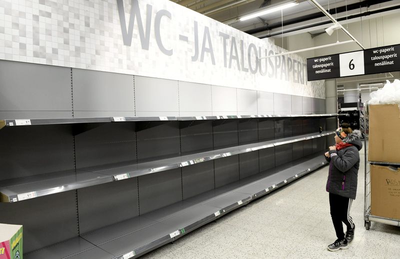 A person walks by an empty toilet paper shelves at a supermarket as consumers worry about product shortages due to the outbreak of the coronavirus disease (COVID-19) in Helsinki