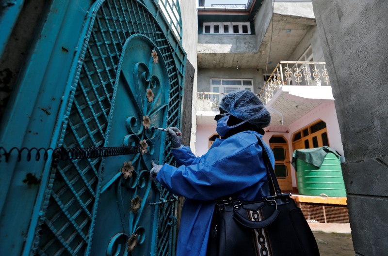 A medic wearing protective suit marks the gate of a house after giving information to the residents about coronavirus disease (COVID-19) during an awareness campaign in Srinagar