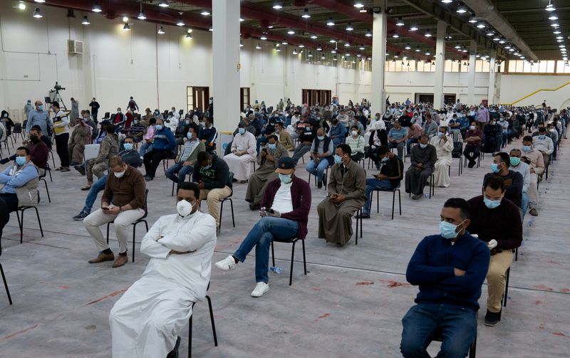 Expatriates wait for mandatory coronavirus testing in a makeshift testing centre in Mishref