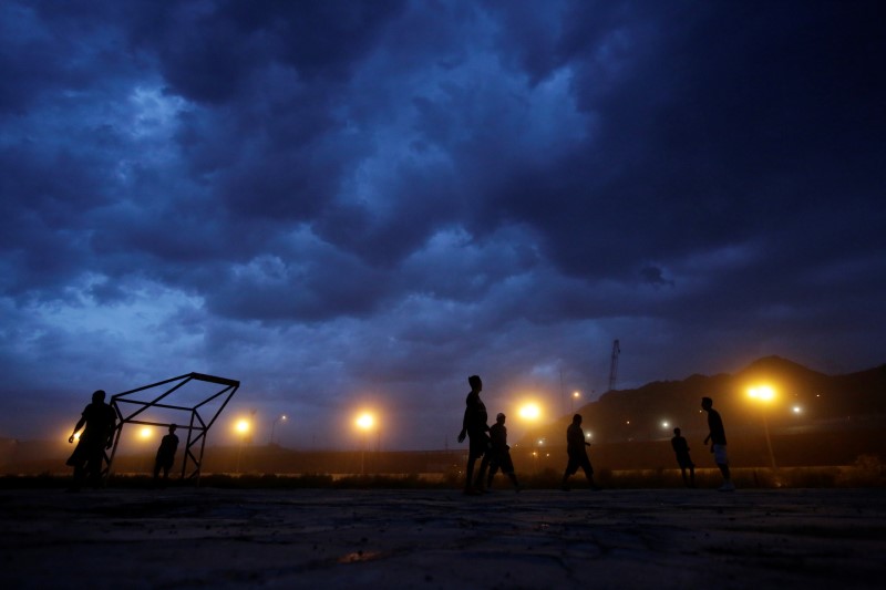 FILE PHOTO: Men play soccer near a section of the U.S.-Mexico border fence as seen from Ciudad Juarez