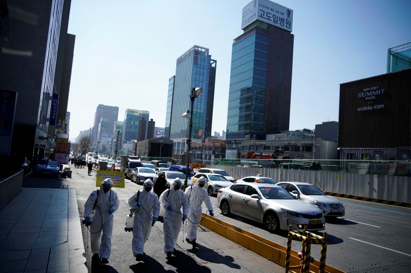 South Korean soldiers in protective gear sanitize a street in Seoul