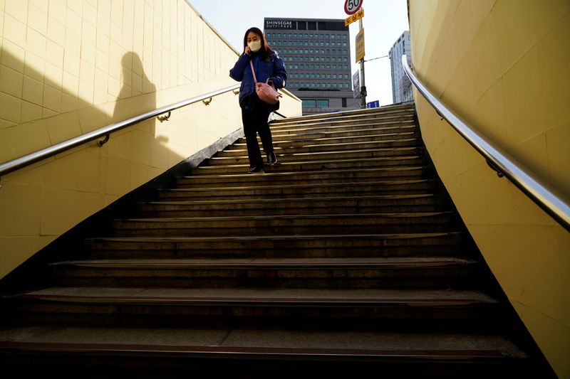 A woman wearing a mask to prevent contracting the coronavirus walks down the stairs in Seoul
