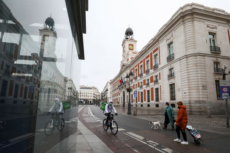 People wearing protective face masks are seen in an almost empty Puerta del Sol in Madrid