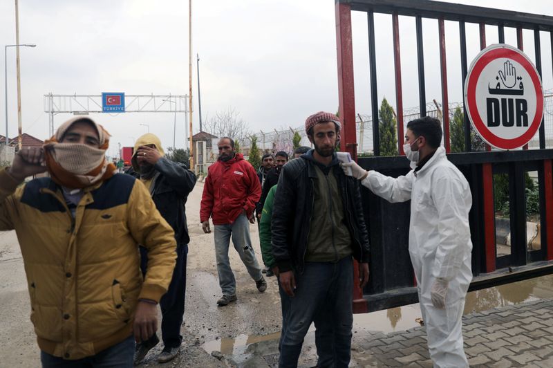 Health worker tests a man as part of security measures to avoid coronavirus, at the Bab el-Salam border crossing between the Syrian town of Azaz and the Turkish town of Kilis