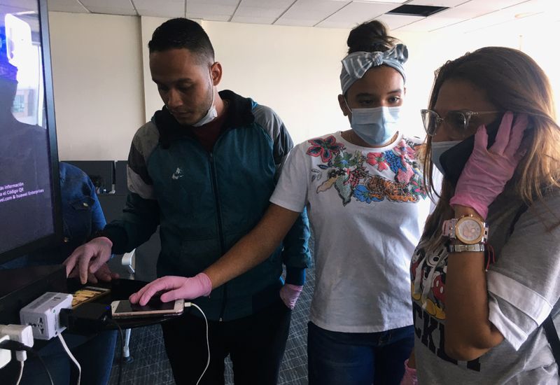 Morles talks on her mobile phone next to her daughter as Brayan Graterol checks his mobile phone at the Tocumen International Airport amid travel restrictions due to the outbreak of coronavirus disease (COVID-19), in Panama City