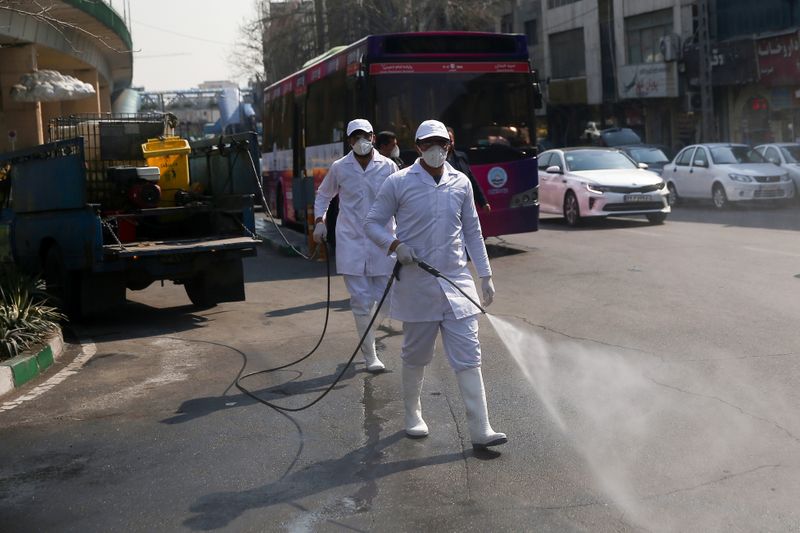 Members of the medical team wear protective face masks, following the coronavirus outbreak, as they spray disinfectant liquid to sanitise streets in Tehran