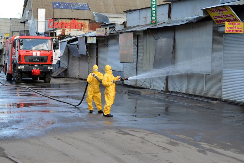 Emergency service members wearing protective suits spray disinfectant at the market in Khmelnytskyi