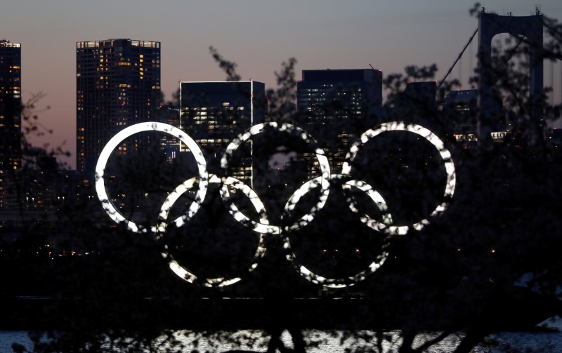 The giant Olympic rings are seen in the dusk through a tree at the waterfront area at Odaiba Marine Park after postponing Games due to the outbreak of coronavirus disease (COVID 19), in Tokyo