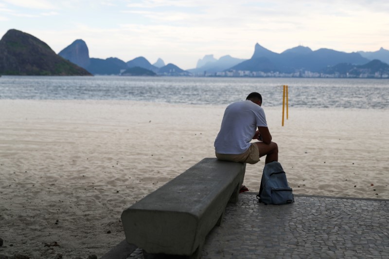 FILE PHOTO: A man sits on a bench at the Icarai beach, banned for users during the coronavirus disease (COVID-19) outbreak, in Niteroi