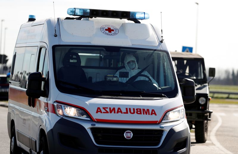 A man wearing a protective face mask drives an ambulance as he leaves the cordoned area in a 