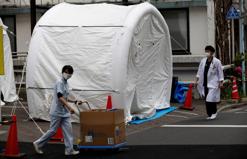 Medical workers walk by tents set up to test for the coronavirus disease (COVID-19) infection at Kawakita General Hospital in Tokyo