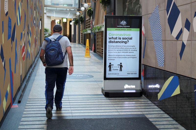 FILE PHOTO: A man walks in a corridor near a sign with instructions about the coronavirus and social distancing following the implementation of stricter social-distancing and self-isolation rules to limit the spread of the coronavirus disease (COVID-19)