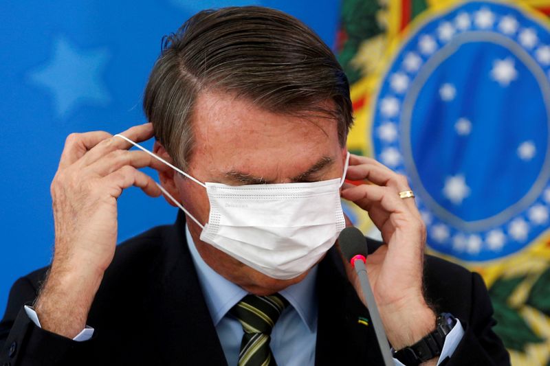 FILE PHOTO: Brazil's Jair Bolsonaro adjusts his protective face mask during a news conference to announce measures to curb the spread of the coronavirus disease (COVID-19) in Brasilia