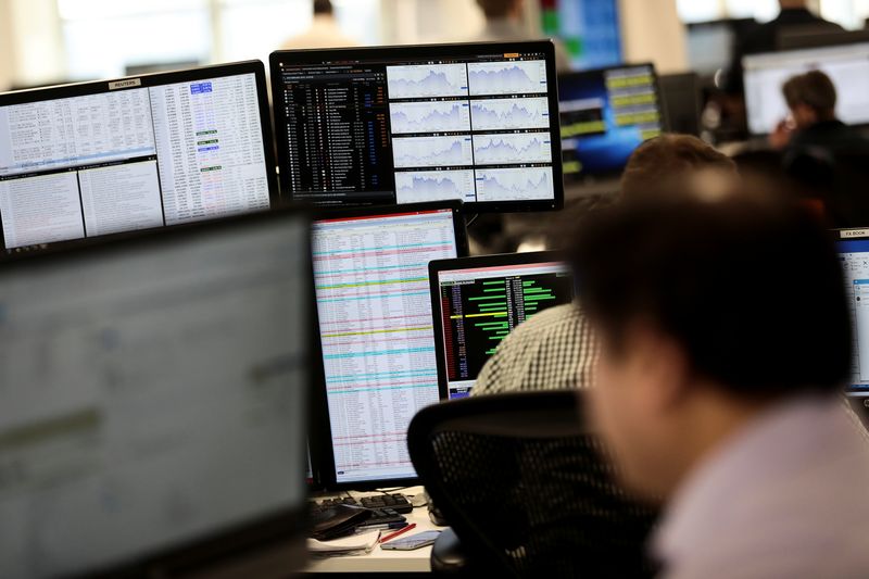 FILE PHOTO: Traders looks at financial information on computer screens on the IG Index trading floor