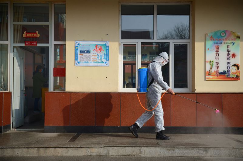 Worker in a protective suit sprays disinfectant at a middle school in Hohhot