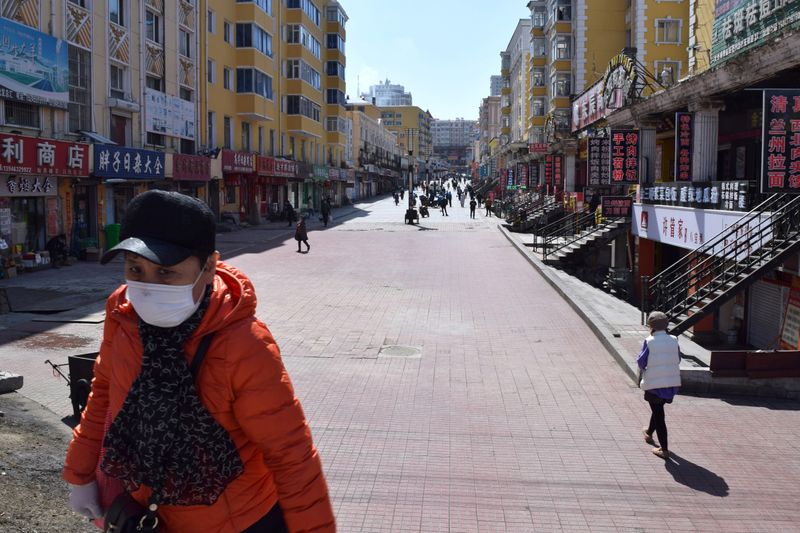 Resident wearing a face mask walks past a shopping street which used to be packed with people in Suifenhe, a city of Heilongjiang province on the border with Russia, as the spread of the novel coronavirus disease (COVID-19) continues in the country