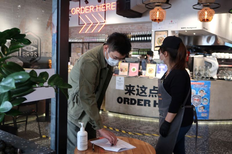 Customer wearing a face mask writes down his information as he enters a Moka Bros restaurant in Beijing, following the novel coronavirus disease (COVID-19) outbreak in the country