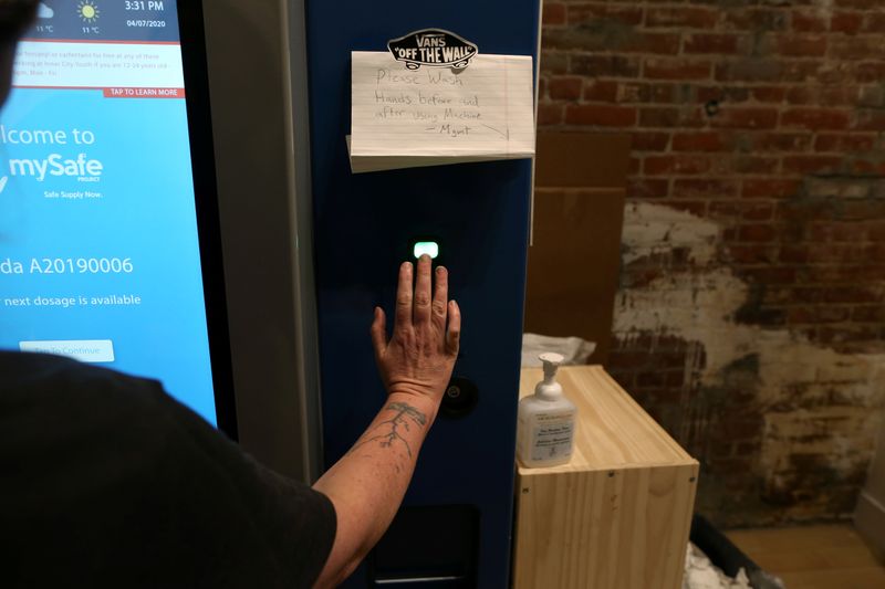 A woman demonstrates how the mySafe narcotic dispensing machine works in Vancouver